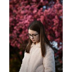 Portrait of beautiful woman standing by pink flower