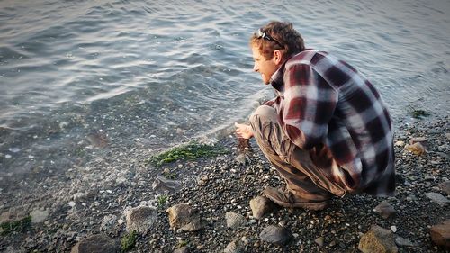 Side view of man crouching at beach