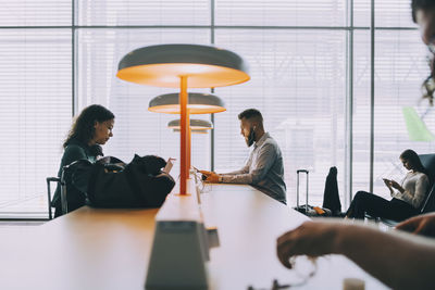 Business colleagues waiting while sitting in departure area of airport