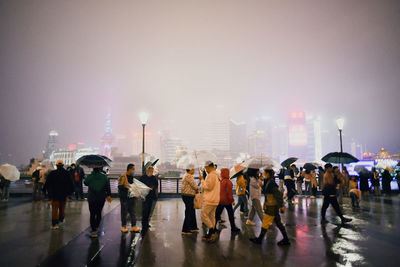 Group of people walking on wet street in city