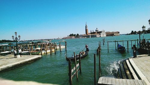 Boats in harbor against clear blue sky