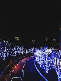 Illuminated city against sky at night