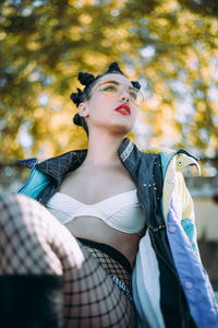 Low angle view of young woman sitting against trees