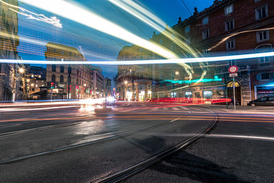 Light trails on city street by buildings at night