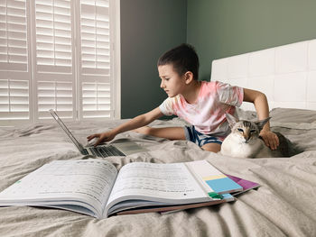 Full length of boy using laptop at home