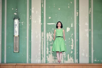 Portrait of a smiling young woman standing against door