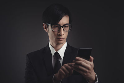 Young man using smart phone against black background