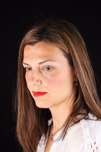 Close-up of young woman against black background