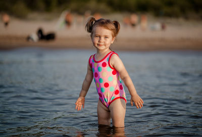 Portrait of cute girl standing in sea at beach