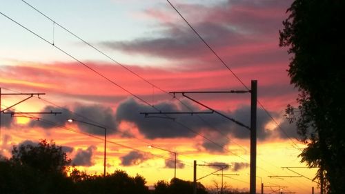Low angle view of electricity pylon against cloudy sky