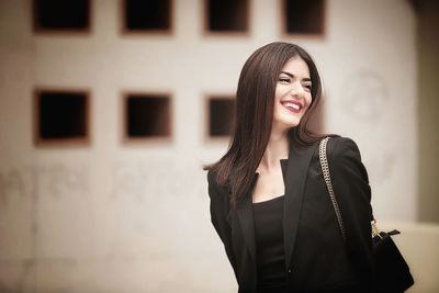 Portrait of young woman standing against wall