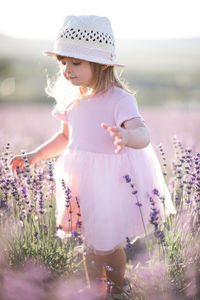 Cute girl wearing hat standing in flower field