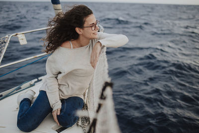 Full length of young woman standing against sea