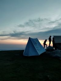 People at tent against sky during sunset