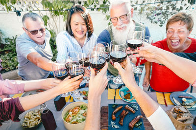 High angle view of happy family toasting drinks while sitting in yard