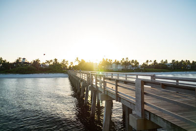 Pier over lake against clear sky during sunset