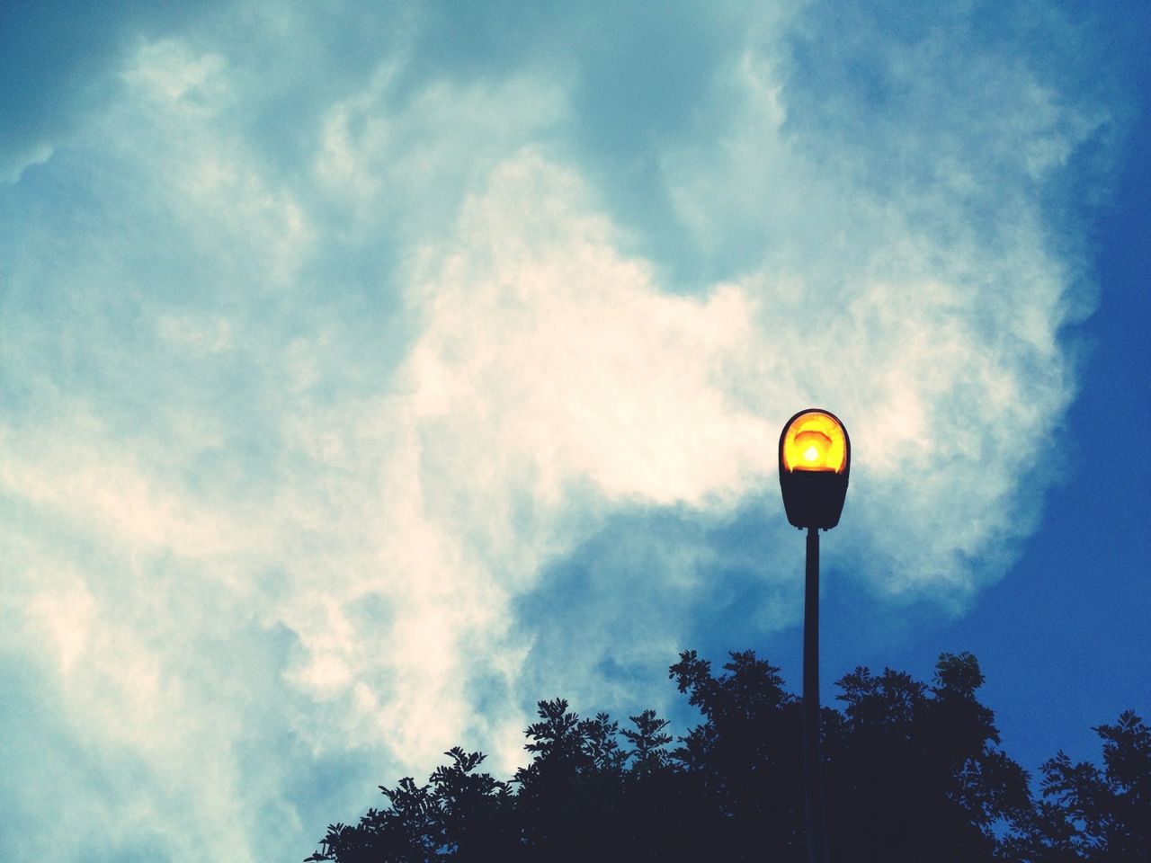 LOW ANGLE VIEW OF STREET LIGHTS AGAINST CLOUDY SKY