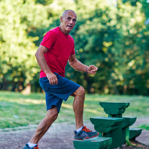 Full length portrait of happy man sitting in park