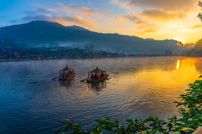 Gondola boat in the middle of a mist-covered lake at sunrise in mae hong son province, thailand