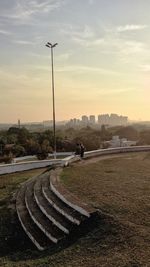 Street by field against sky during sunset