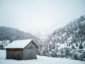 House on snow covered field against clear sky