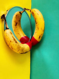 Close-up of red tipped bananas on mirror on yellow and green background.
