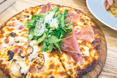 High angle view of parma ham and rocket leaves on pizza