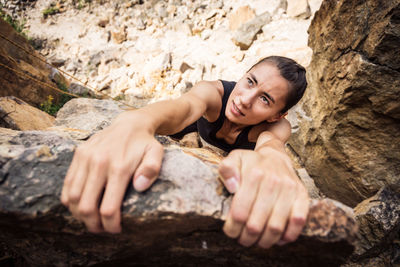 High angle portrait of young woman sitting on rock