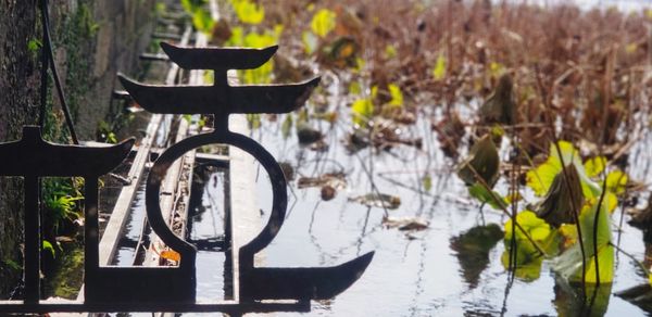 Close-up of empty chair on table by lake