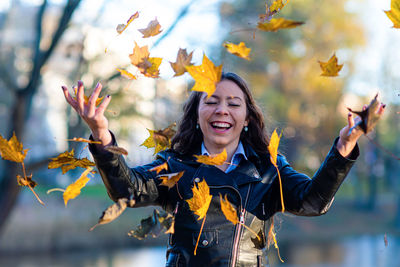 Woman standing while throwing leaves during autumn