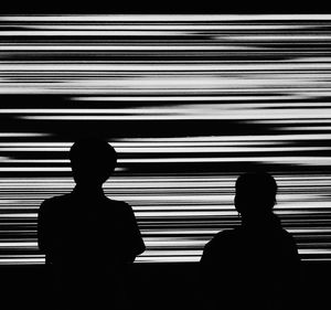 Rear view of silhouette people against blinds in darkroom
