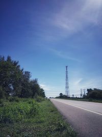 Road amidst field against the blue sky and communication tower