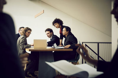 Team of multi-ethnic lawyers discussing strategy over laptop in meeting at office