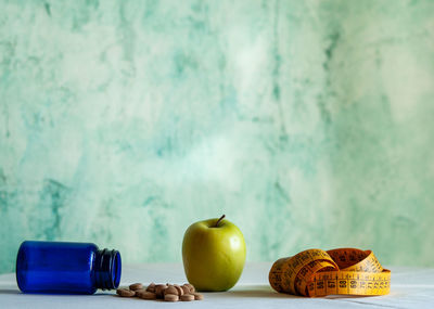 Close-up of apples on table against wall