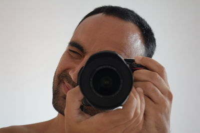 Portrait of man photographing against white background