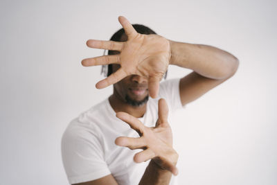 Midsection of man with arms raised standing against white background