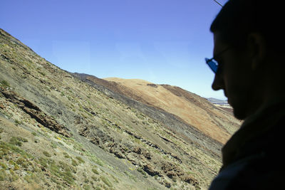 Portrait of young woman looking at mountains against sky