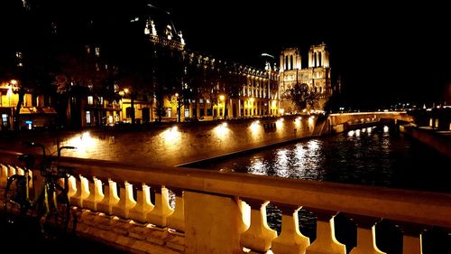 Illuminated bridge over river in city at night