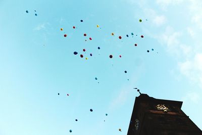 Low angle view of balloons flying against blue sky