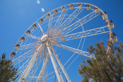 Low angle view of ferris wheel against blue sky