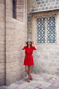 Woman in red dress with hat and sunglasses standing in the old town