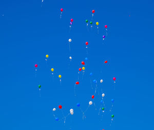 Low angle view of balloons flying against blue sky