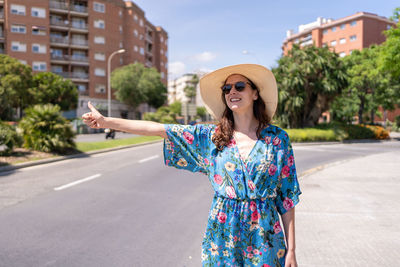 Portrait of smiling young woman standing on road in city