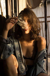 Portrait of young woman smoking cigarette at home