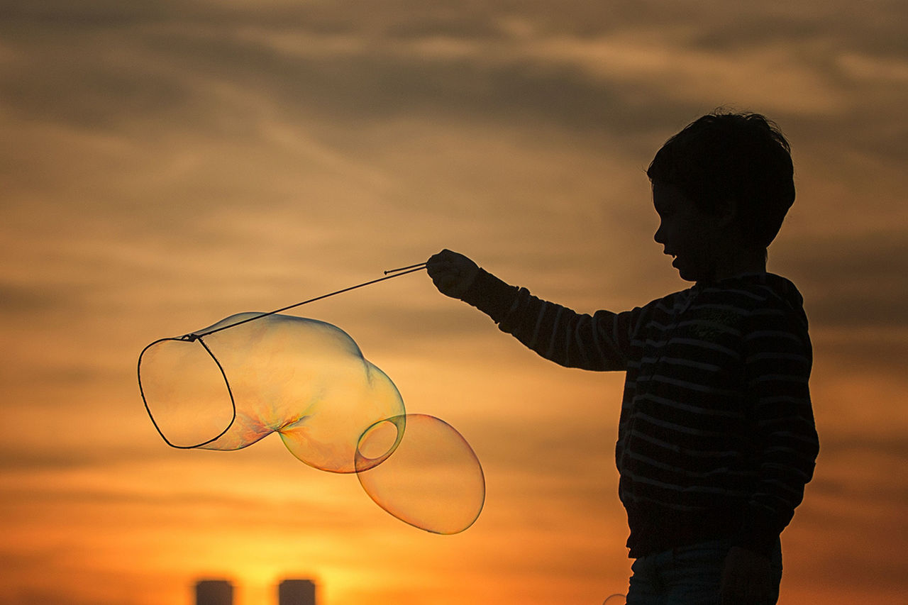 sky, sunset, silhouette, leisure activity, lifestyles, men, cloud - sky, standing, holding, rear view, cloud, childhood, orange color, dusk, outdoors, focus on foreground, three quarter length, boys