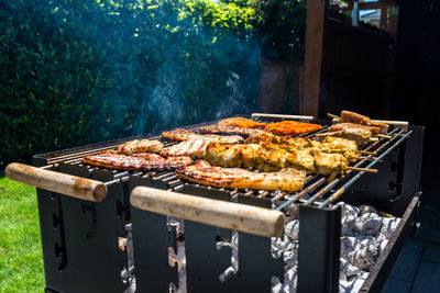 Different types of meat fried on the home grill, standing on a home garden on the paving stone.