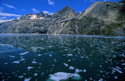 Scenic view of lake by snowcapped mountains against sky