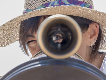 Close-up portrait of woman looking through hand-held telescope