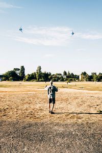 Full length of person flying bird on field against sky
