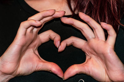 Midsection of woman making heart shape
